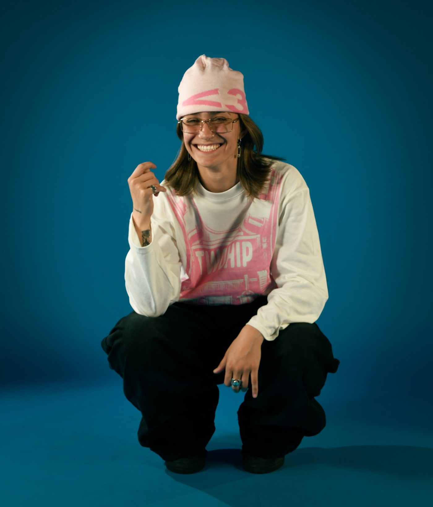 JAZ sonriendo, con gorro rosa, sobre fondo azul
